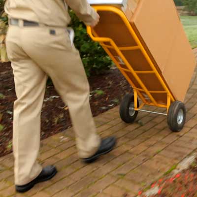 man pushing a dolly with big box on it